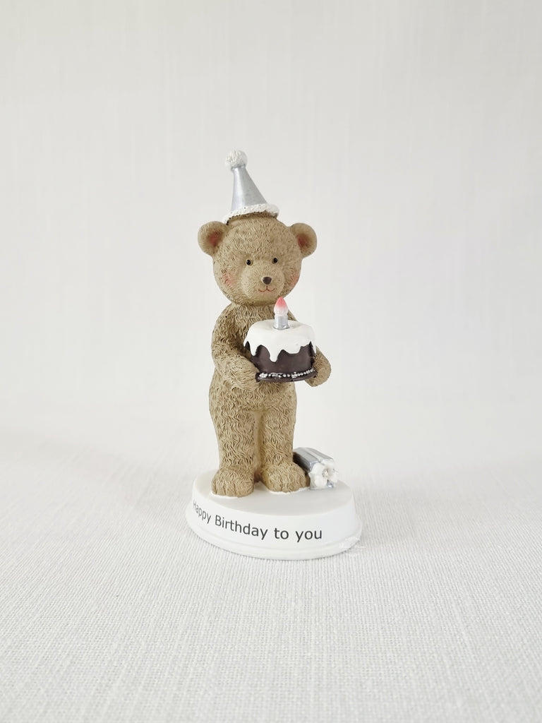 Teddy bear figurine with a birthday cake and candle on a white base with 'Happy Birthday to you' text.